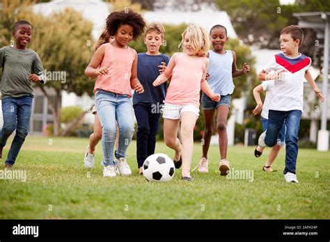 Group Of Children Playing Football With Friends In Park Stock Photo Alamy