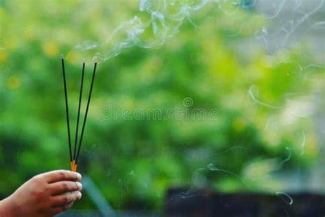 Two Agarbatti Rises Smoke Hold In Hand With Green Background Stock