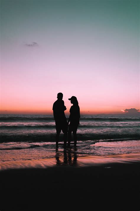 Silhouette Of Couple Walking On Beach During Sunset · Free Stock Photo