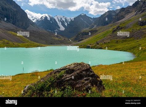 Turquoise Clear Water Of The Karakabak River Among Stones And Grass In