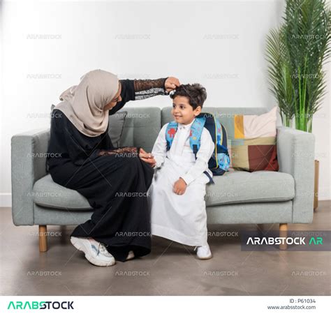 أم عربية خليجية سعودية تقوم بتجهيز ابنها للذهاب الى المدرسة، ارتداء الزي المدرسي، الاستعداد
