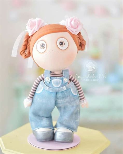 A Small Doll With Red Hair And Blue Overalls Sitting On Top Of A Table