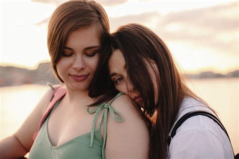 Portrait Of Happy Lesbian Couple Standing On Bridge At Sunset Photograph By Cavan Images