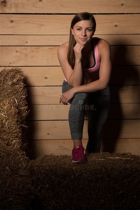 Attractive Young Woman In Sporty Dress In A Barn Posing With Hay Stock