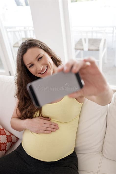 Taking A Selfie For Two A Young Pregnant Woman Taking A Selfie With