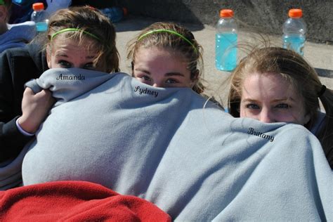Three Girls Wrapped Up In Blankets With Water Bottles On The Ground Behind Them And One Girl
