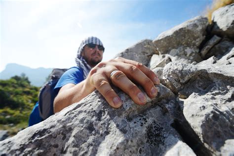 Young White Man Climbing A Steep Wall In Mountain Rock Climbing And