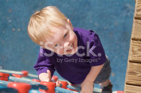 Boy Looks Up From Climbing A Playground Rope Ladder Stock Photo