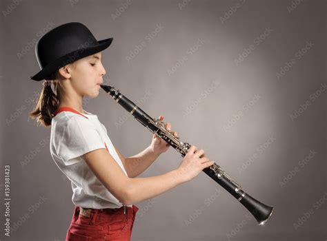 Foto Stock Little Girl Playing Clarinet On A Gray Background Adobe Stock