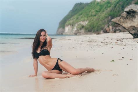 Tanned Girl In Black Swimsuit Posing On Sandy Beach Near Ocean Beautiful Model Sunbathes And