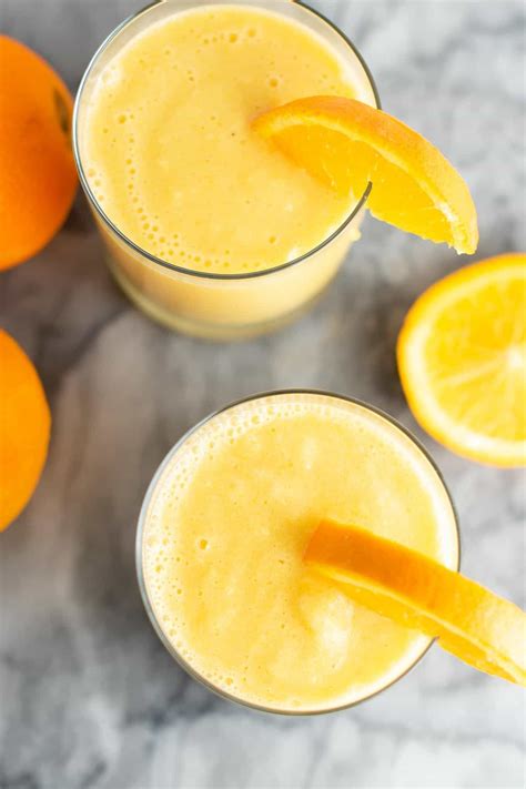 Orange Smoothie In A Clear Glass With A Slice Of Orange On The Rim From