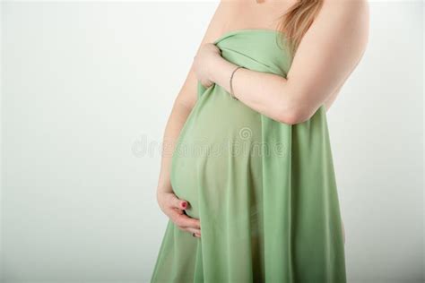 Beautiful Pregnant Girl Is Standing And Holding Her Stomach In A Green Cloth On A White
