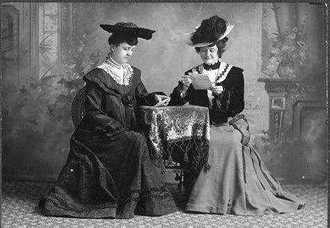 Two Ladies In Beautiful Dress And Hats Seated At A Table · Tadl Local