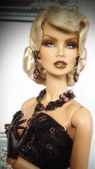 A Barbie Doll With Blonde Hair And Black Dress Holding Her Hand On Her