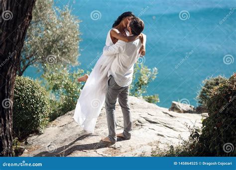 Man Holding Woman In His Arms Wrapped Around Her Waist And She Is