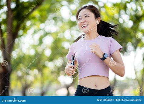 healthy asian woman smiling while running in the park in the morning she is exercising while