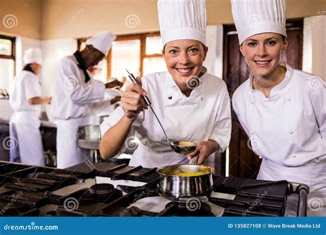 Female Chefs Putting Baking Tray Of Kaiser Rolls In Oven Stock Image
