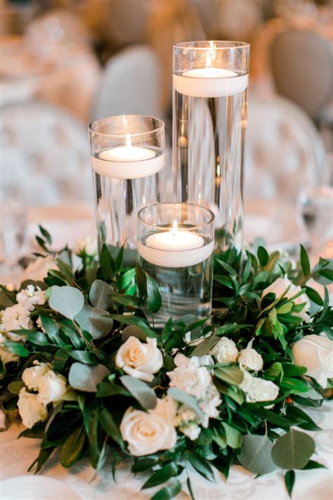Varying Height Floating Candles On Organic Greens And White Flowers