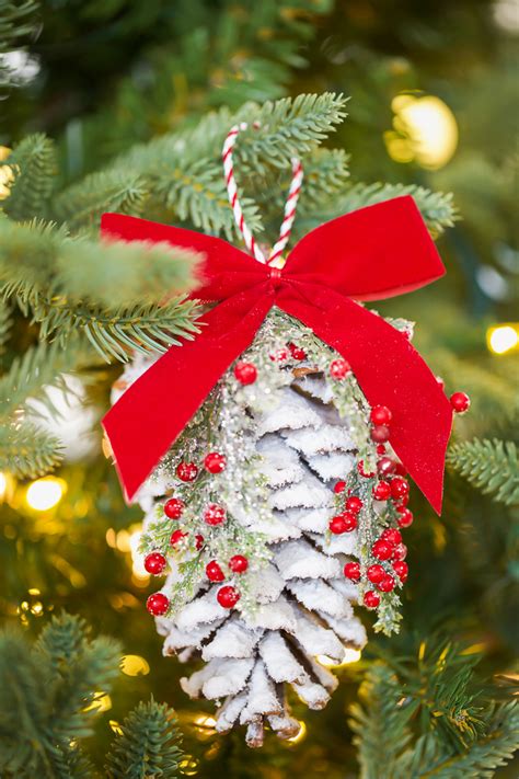 A Pine Cone Ornament Hanging From A Christmas Tree With Red Ribbon And Bow