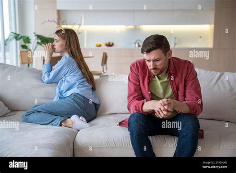 Couple Man Woman Ignoring Each Other Sitting On Couch In Silence At Home Turning Away Stock