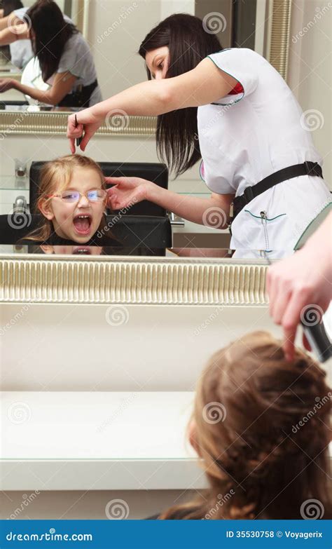 Hairdresser Combing Hair Little Girl Child In Hairdressing Beauty Salon