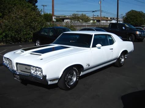 A White Muscle Car Parked In A Parking Lot