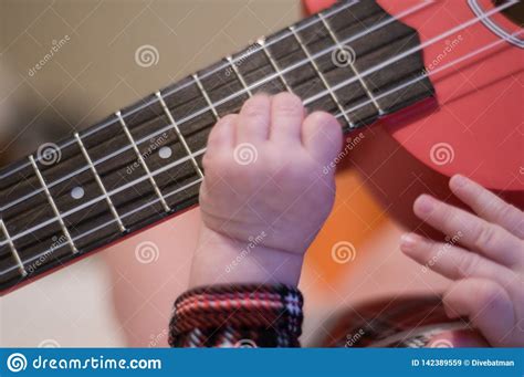 Baby Fingers Plays Guitar Ukulele Strings And Frets Stock Image