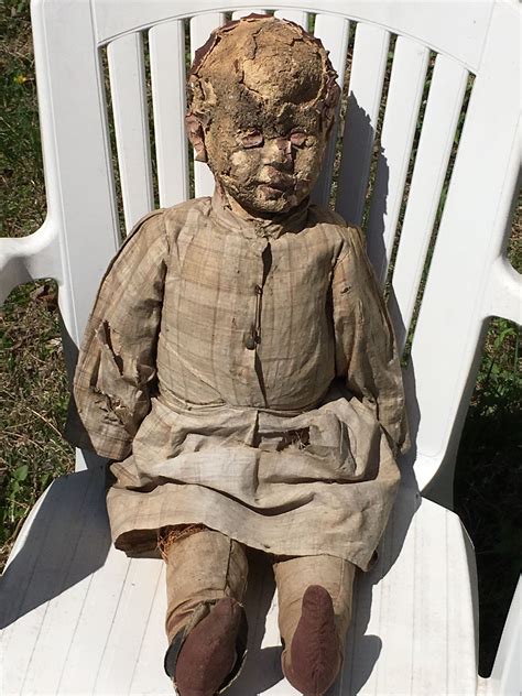 An Old Doll Is Sitting On A White Chair