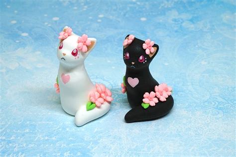Two Black And White Cat Figurines Sitting Next To Each Other On A Blue