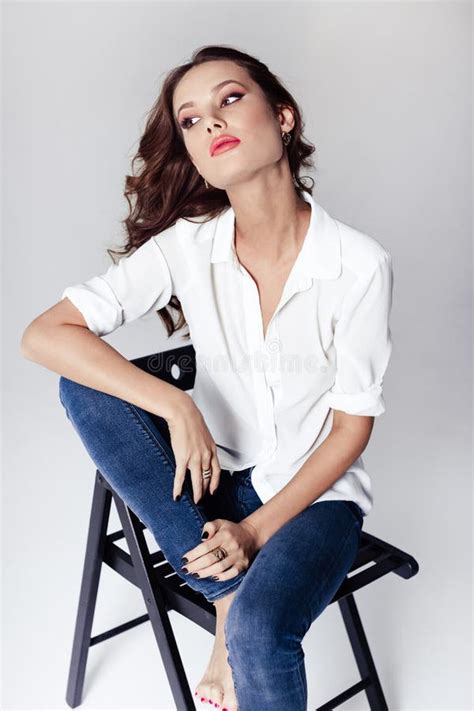 Fashion Model Sitting On A Chair In A Blouse And Jeans Barefoot Stock