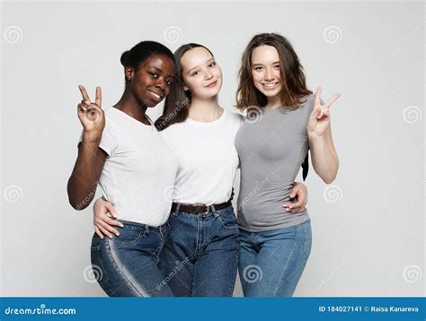 Portrait Of Young Multiracial Women Standing Together And Smiling At Camera Isolated Over White