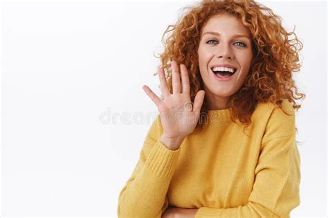 waist up cheerful smiling redhead curly woman silly and coquettish grinning as waving her palm