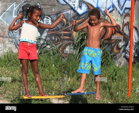 Children Play On Swing In Rio De Janeiro Favela Slum With Graffiti
