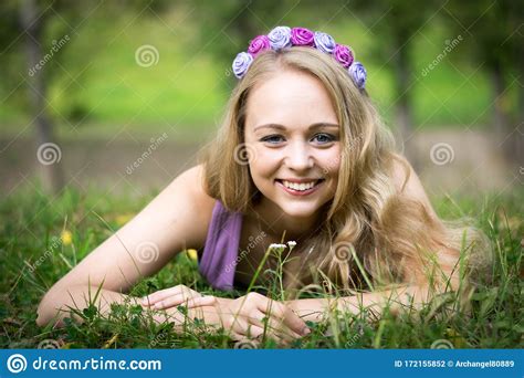 Beautiful Blonde Girl Lying In The Grass And Smiling Stock Photo
