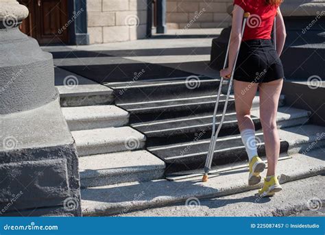 Young Woman With Ankle Injury Climbs Stairs On Crutches Stock Image