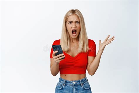 Angry And Frustrated Blond Girl Screams Holds Mobile Phone And Shouts