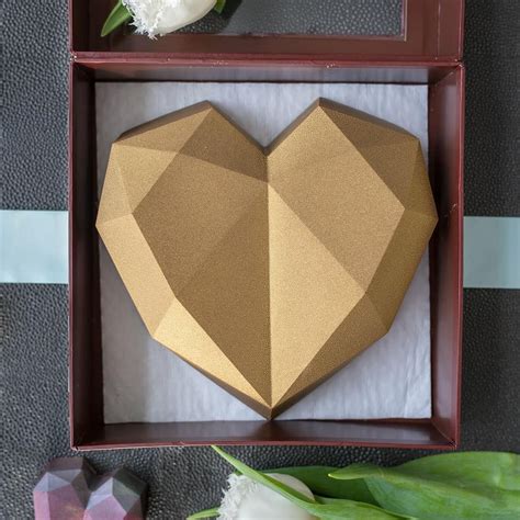 An Origami Heart In A Wooden Box With Flowers On The Table Next To It