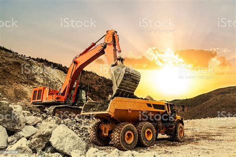 excavator loading dumper truck  mining site stock photo