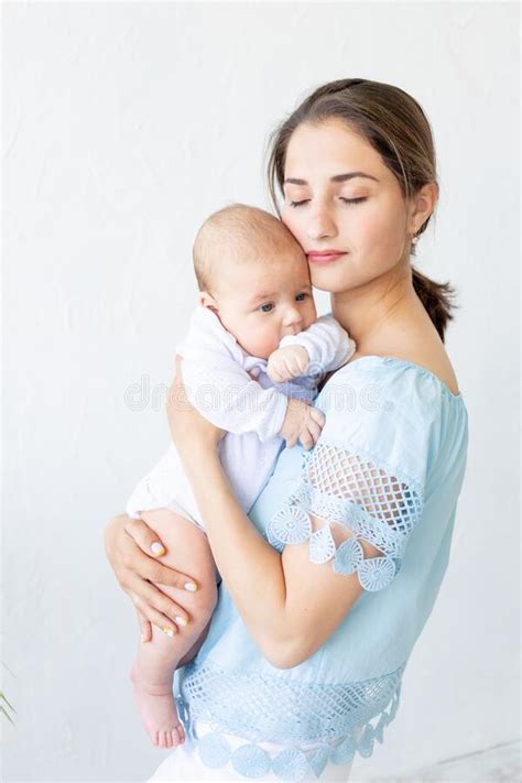 A Young Mother With A Newborn Baby Gently Holds It In Her Arms Hugging