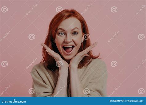 surprised beautiful ginger woman spreading palms near face and keeping mouth open from