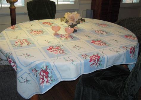A Dining Room Table With A Flowered Tablecloth On It And Two Chairs In