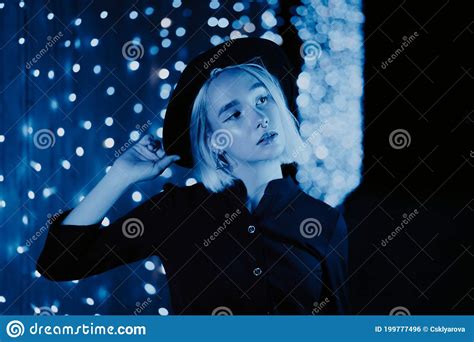 Millennial Enigmatic Pretty Girl Blond Hairstyle Near Blue Glowing Neon