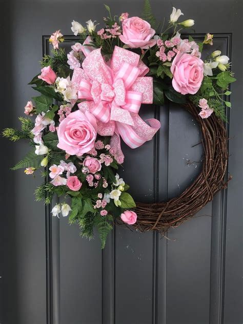 A Wreath With Pink Roses And Green Leaves On The Front Door Is
