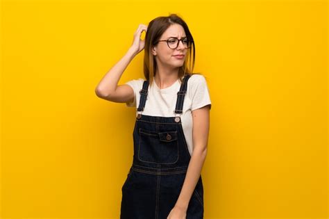 Premium Photo Woman Over Yellow Wall Having Doubts While Scratching Head