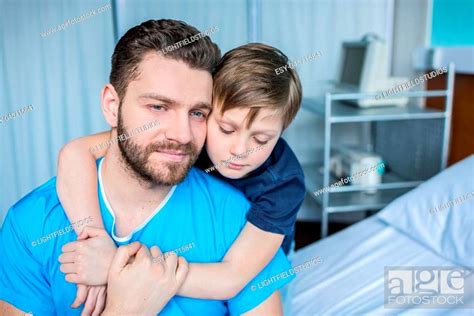 Father And Son Hugging While Sitting On Hospital Bed Dad And Son In