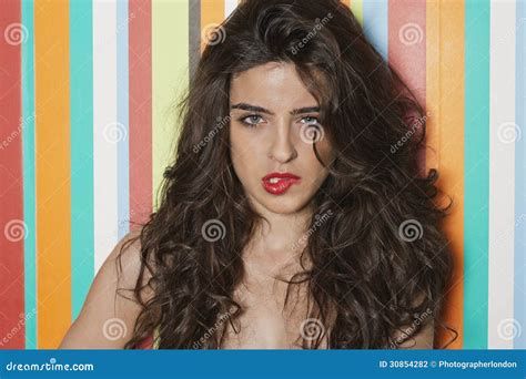 Portrait Of A Sensuous Young Woman Biting Lips Against Colorful Striped