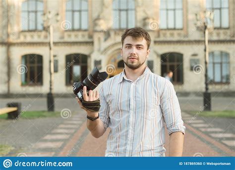 Handsome Young Male Photographer Stands With Camera In Hand On