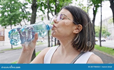 Young Beautiful Hispanic Woman Standing Drinking Water At The Park In