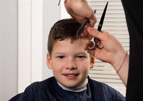Hairdresser Boy Does A Haircut With Scissors And Comb Stock Photo