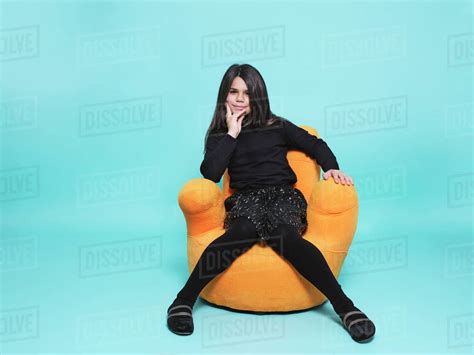 Preteen Girl In Black Casual Clothes Resting Hand On Chin Looking At Camera While Relaxing In